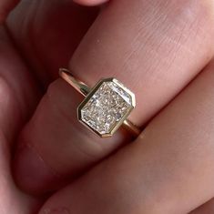 a close up of a person's hand holding a diamond ring