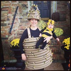 a woman holding a baby wearing a bee costume