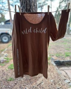 This is a brown long sleeve shirt with a white glittery vinyl lettering across the chest. The lettering on the sleeve is in silver. A unique AZ Wild Child design! Brown Long Sleeve Cotton T-shirt, Brown Long Sleeve Top With Graphic Print, Long Sleeve T-shirt With Lettering, Brown Long Sleeve Graphic T-shirt, Brown Long Sleeve Tops With Letter Print, Brown Long Sleeve Top With Letter Print, Long Sleeve Name Print Tops For Fall, Long Sleeve Tops With Name Print For Fall, Brown Long Sleeve Shirt