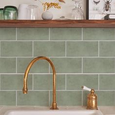 a kitchen sink with gold faucet next to a shelf filled with vases