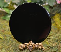 a black plate sitting on top of a moss covered ground