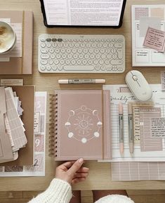 a person is sitting at a desk with notebooks, papers, and a computer