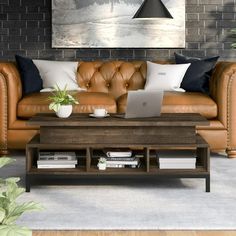 a brown leather couch sitting next to a wooden table with a laptop on top of it