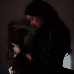 two people standing next to each other in the dark with their arms around one another