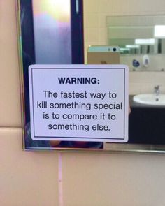 a warning sign posted on the side of a bathroom wall next to a sink and mirror