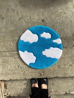 a person standing in front of a rug with clouds on it