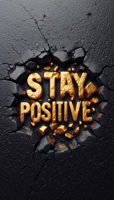 the words stay positive written in gold on a black surface with cracked paint and cracks