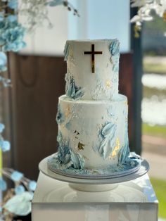 a white and blue wedding cake with a cross on top