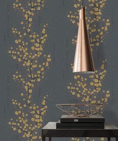 a lamp hanging over a table next to a wall with gold paint splattered on it