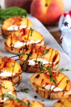 grilled peaches with goat cheese and basil on a sheet of parchment paper next to fresh fruit