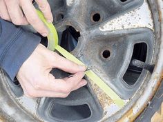 a person using a pair of scissors to cut holes in the rim of a tire