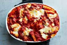 a plate of pasta with sauce and cheese on top, sitting on a black napkin