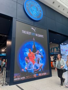 people are walking by a large poster in the middle of an airport