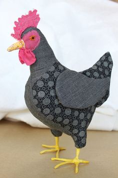 a black and white chicken standing on top of a wooden floor next to a pillow