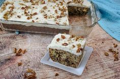 a piece of carrot cake on a plate next to a glass dish with one slice missing