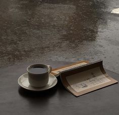 a cup of coffee sitting on top of a table next to an envelope and umbrella