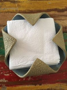 a white napkin sitting on top of a wooden table next to a brown and white plate