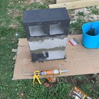 an outdoor fireplace being built with tools on the ground next to it and other items