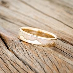 a gold wedding ring sitting on top of a wooden table