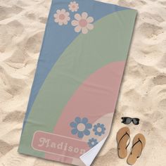 a towel, pair of flip flops and sunglasses on the sand at the beach