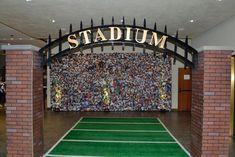 an indoor stadium with green turf and brick pillars in front of a wall that reads stadium