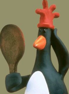 a black and white penguin with a red hat holding a wooden spoon in its hand