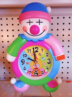 a colorful clock with a clown face on it's face is sitting on a shelf