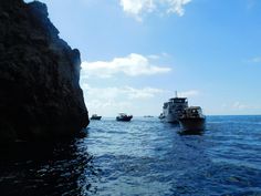 several boats in the water near some rocks