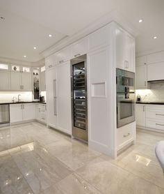 a large kitchen with white cabinets and marble flooring is pictured in this image, there are lights on the ceiling