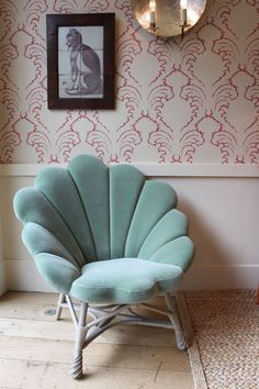 a blue chair sitting in front of a wall with a cat on it's back