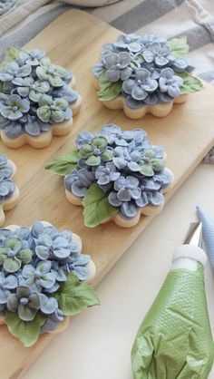 blue and green flowers are placed on top of cookie cookies with icing cutters next to them