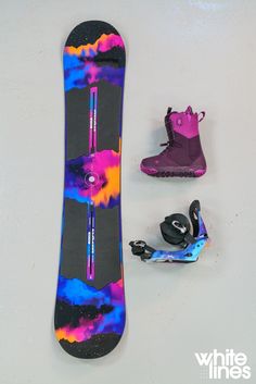 the snowboard is next to two pairs of skis and one pair of boots