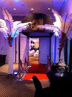 the entrance to a hotel decorated with tall white feathers and blue lights on either side