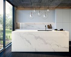 a modern kitchen with marble counter tops and white cabinetry, along with hanging lights