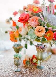 a vase filled with lots of flowers sitting on top of a table next to two wine glasses