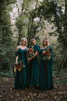 three bridesmaids in green dresses stand together in the woods with their bouquets