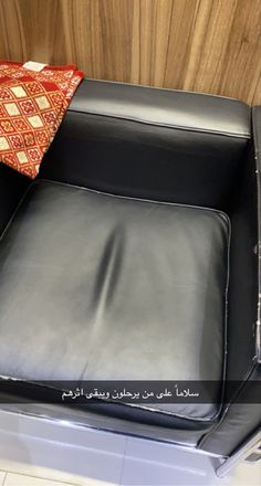 a black leather chair with a red pillow on it