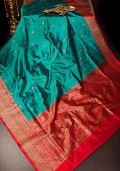 Raw silks are understated elegance! This gorgeous saree comes in a teal and red with antique zari detailing! SILK MARK CERTIFIED This saree is ready to wear with fall and pico done. Hand made tassels line the pallu. An unstitched blouse fabric is included. *Note: There may be minor variations in the shade, the texture of the product. Hues/textures show differently due to variations in screen settings and other factors, *Note: This is a handmade saree and there may be slight inconsistencies such as in it's weaving. These are characteristic of handmade products and attest to their originality and are not considered as defects. Handmade Saree, Gorgeous Saree, Raw Silk Saree, Understated Elegance, Blouse Fabric, Handmade Products, Raw Silk, Saree Blouse, Silk Saree