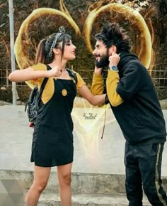 a man and woman standing next to each other in front of a wall with gold rings on it