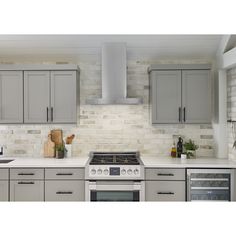 a kitchen with gray cabinets and white counter tops, an oven and stove hood in the middle