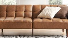 a brown leather couch with two pillows on it