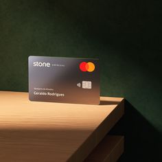 a stone credit card sitting on top of a wooden table next to a green wall