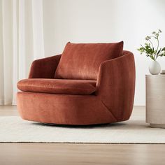 an orange chair sitting on top of a wooden floor next to a potted plant