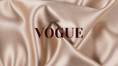 the word voque is written in brown on a light beige satin background with some folds