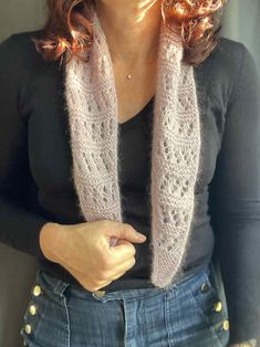 a woman wearing a knitted scarf with buttons on the bottom and one hand in her pocket