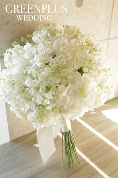 a bouquet of white flowers sitting on top of a wooden floor next to a wall