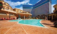 an empty swimming pool in the middle of a building with a large hotel behind it