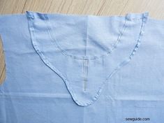 a blue shirt is laying on top of a wooden table and the fabric has been stitched together