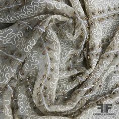 an up close photo of a fabric with white and grey designs on the side,