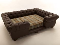 a brown leather couch with a checkered blanket on it's back and footrests